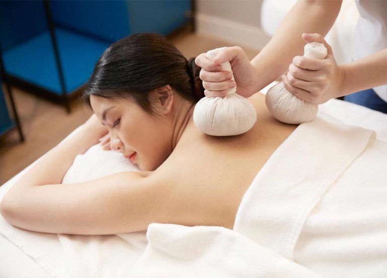 Close-up Of Spa Therapist Performing Herbal Compress Massage On Woman's Shoulders Bangkok Spa Siam SQ1