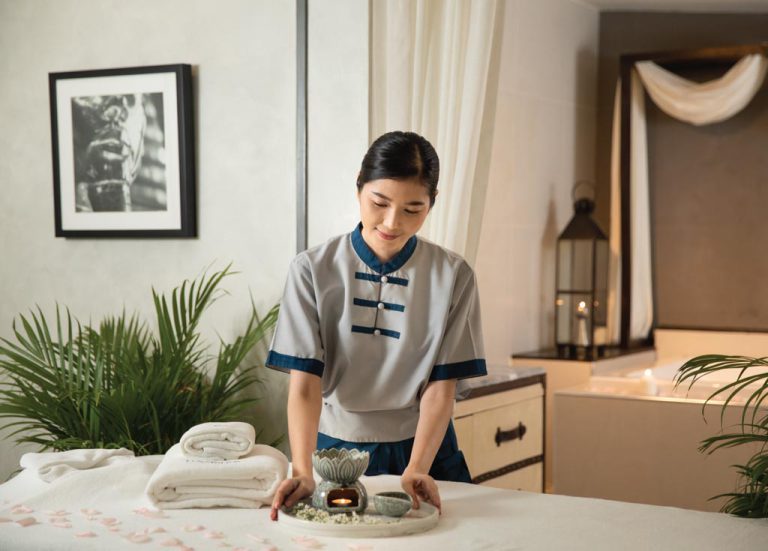 Spa Therapist Preparing Items On Massage Table